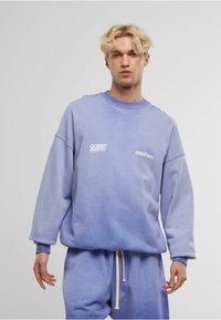 Lichtpaars sweatshirt met een losse pasvorm, geribbelde crew halslijn en contrasterende witte tekst: "ocean swim" en "another." Gecombineerd met bijpassende shorts.