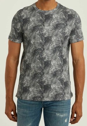 Mand iført kortærmet grå og sort marmoreret T-shirt med lille hvid tekst på brystet, kombineret med falmede blå jeans.