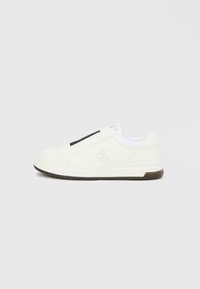 Χαμηλό λευκό αθλητικό παπούτσι με μαύρη ελαστική ταινία, λογότυπο "cK" στο πλάι και μαύρο περιθώριο σόλας σε απλό ανοιχτό γκρι φόντο.