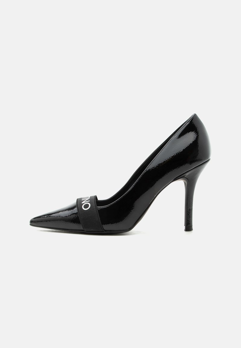 Escarpin à talon haut en cuir verni noir à bout pointu, talon fin et bande élastique sur le devant avec texte blanc.