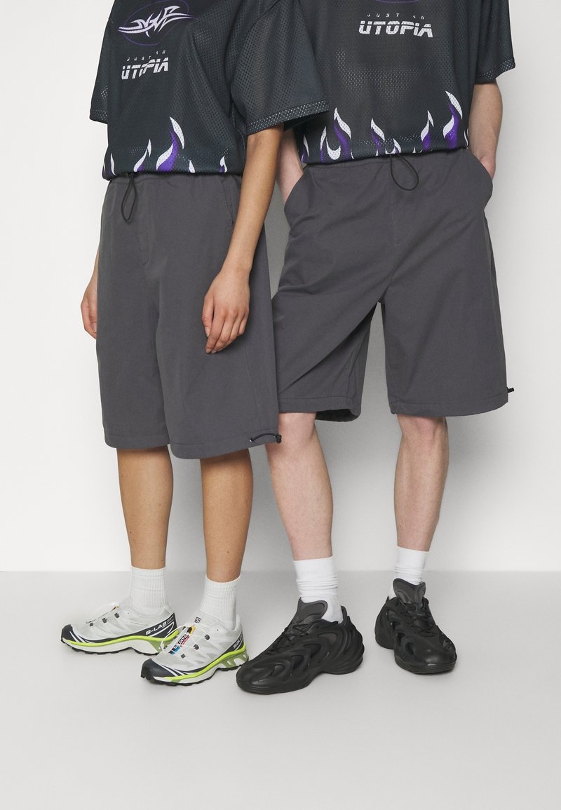 Un short gris avec une coupe décontractée et une taille à cordon de serrage. Complété par des hauts en maille avec des motifs de flammes et deux styles distincts de baskets.