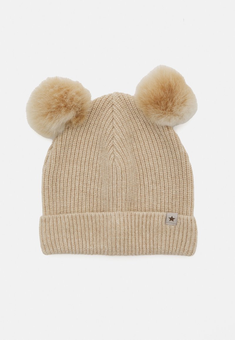 Béžový pletený čepice s ribovanou texturou, dvěma imitacemi kožešiny pom-pom na vrchu a malou látkovou nášivkou se hvězdou na manžetě.