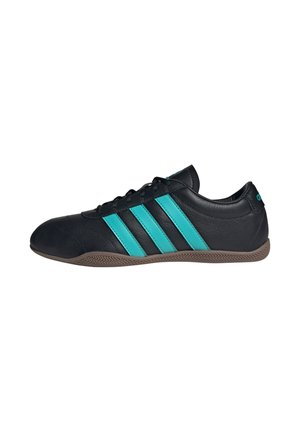 Sort lædersneakers med tre grønblå striber, sorte snørebånd og en brun tekstureret sål, sideview.