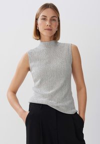 Mouwloze top met hoge hals in textuurwit stof met een subtiel zwart ruitpatroon, gecombineerd met zwarte broek. Soepele, getailleerde pasvorm.