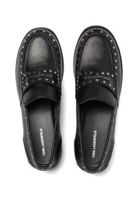 Crne kožne loafers cipele s srebrnim zakovicama duž oboda, podstavljenim ovratnikom i ravnim potplatom. Ime branda vidljivo na ulošku.