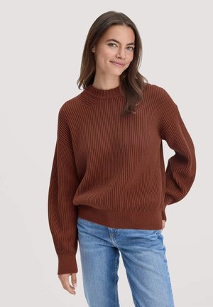 Brauner gerippter Pullover mit Rundhalsausschnitt, lockerer Passform und langen Ärmeln, kombiniert mit hellblauen Jeans. Glatte Textur und entspanntes Design.