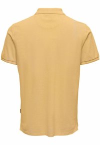 Camisa de polo de algodón amarilla con mangas cortas, un cuello clásico y un dobladillo recto. Sin patrones ni logotipos visibles, se muestra la vista trasera.