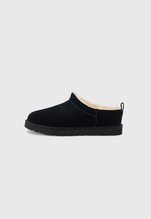 Chaussure noire en daim à enfiler avec une doublure douce de couleur crème, un bout arrondi et une semelle extérieure en caoutchouc noir texturée pour une meilleure adhérence.