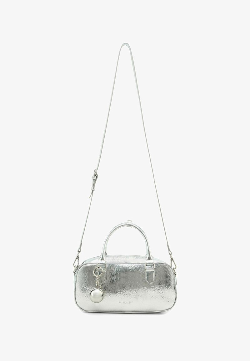 Borsa metallica argentata con texture liscia, forma arrotondata, doppi manici, tracolla rimovibile e un ciondolo rotondo decorativo attaccato.