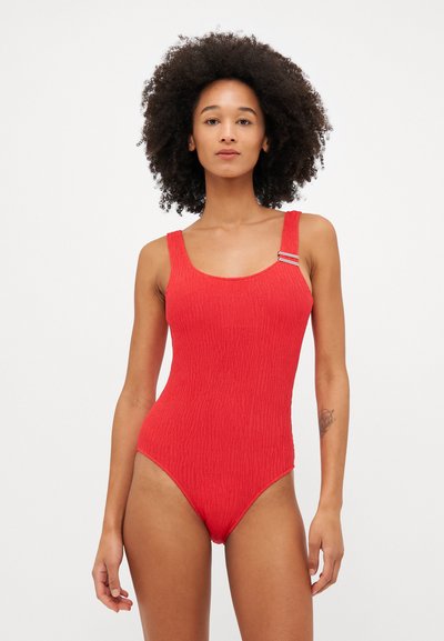 Red one-piece swimsuit with a textured ribbed design, square neckline, wide straps, and metal accent on one strap.