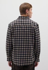 Camicia a quadri in flanella blu navy e beige, con colletto classico, maniche lunghe e polsini con bottoni, presenta un design posteriore a taglio dritto.