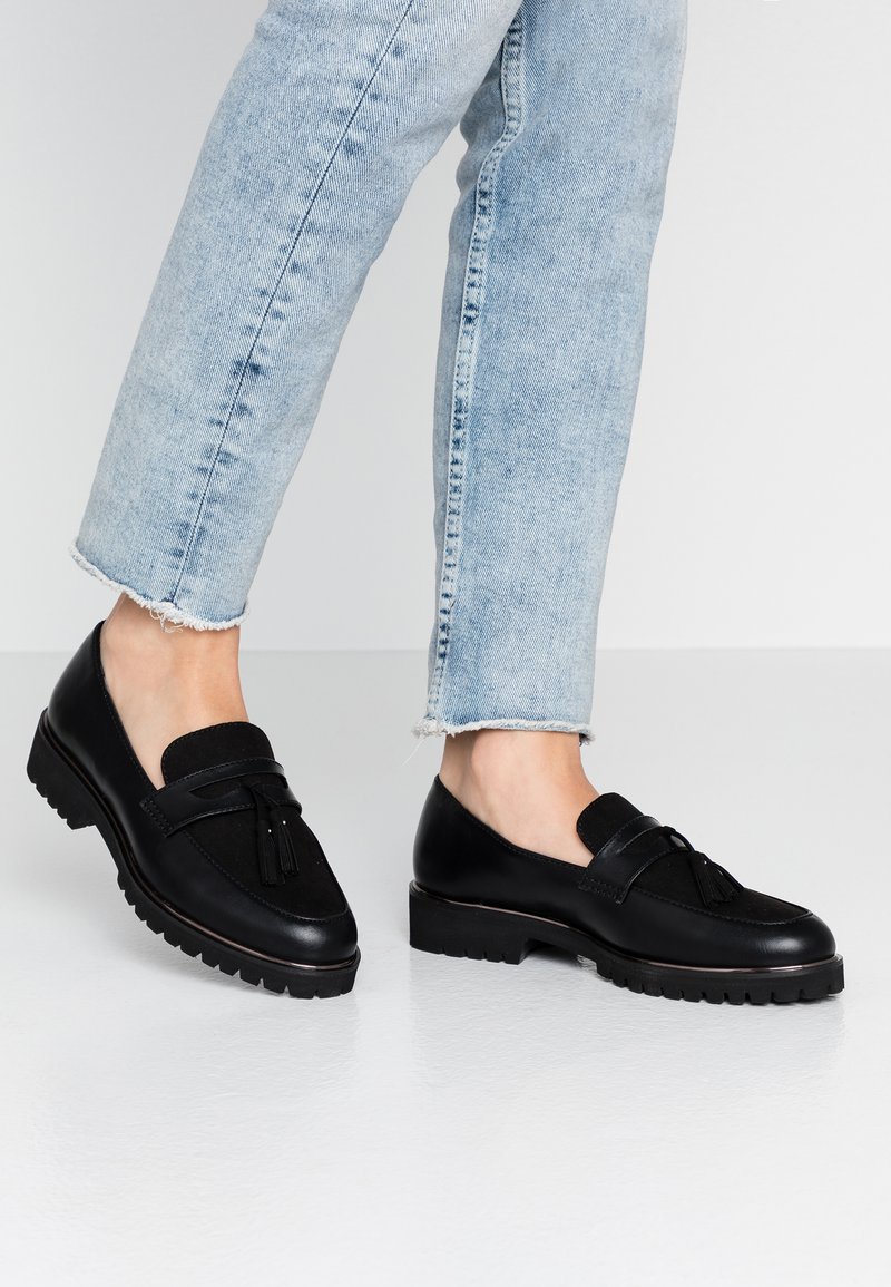 Mustad nahast loafers, millel on sametist aktsent ja pompomdetail. Paks kummitald, sile tekstuur ja ümar varvas. Igapäevane stiil.