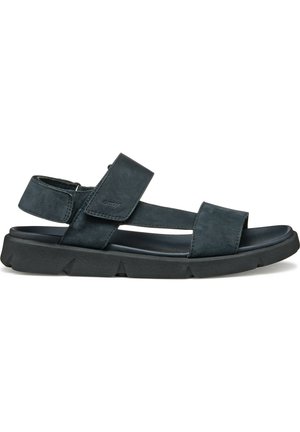 Sandal de color azul oscuro con un diseño de correa ajustable, material de ante suave, plantilla acolchada y suela de goma negra texturizada.