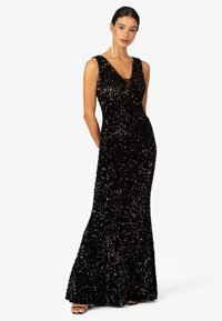 Schwarzes Pailletten-Abendkleid mit tiefem V-Ausschnitt, ärmellosem Design, tailliertem Oberteil und schwingendem Rock. Transparenter Einsatz am Ausschnitt.