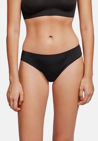 Bikini de algodón negro con mezcla de tejidos, con una cintura de corte bajo, bordes de cinturilla con forma de ondas y un diseño minimalista. Textura suave.