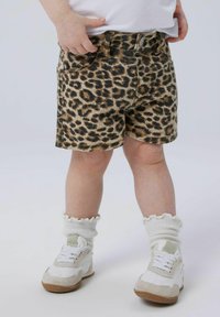 Löpartryckta jeansshorts med fem fickor, en knäppning och fransad nederkant. Parades med vita och beige sneakers och ribbade strumpor.