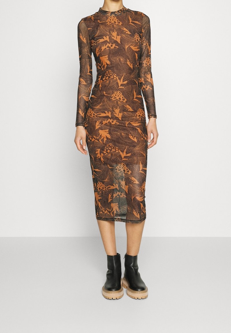 Robe ajustée à manches longues en tissu marron transparent avec un imprimé botanique orange. Associée à des bottines noires à semelles épaisses.