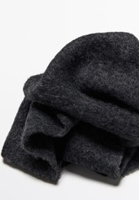 Sciarpa in lana nera, piegata, con una superficie morbida e texturizzata. Presenta fibre sciolte e una forma leggermente irregolare.