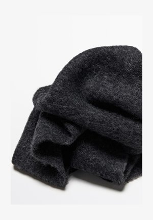 Svart ullsjal, vikt, med en mjuk, strukturerad yta. Har lösa fibrer och en något oregelbunden form.