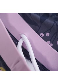 Färgglada tygskikt, med ett lila elastiskt band, en strukturerad nätsektion och en floral mörk bakgrund med en vit dragsko.