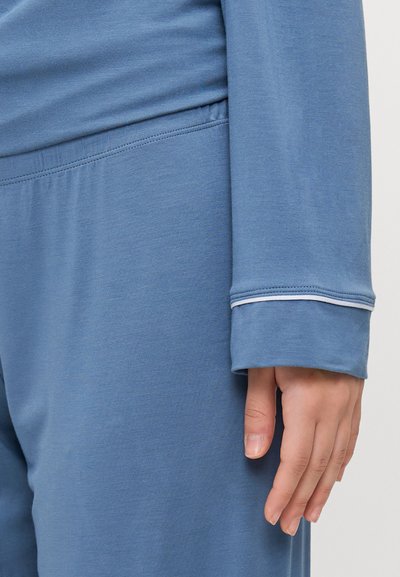 Blue long-sleeve top with light-colored stitching at the cuff, paired with matching loose-fitting pants, both made of soft, smooth fabric.