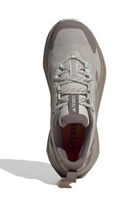 Light gray athletic shoes with a textured mesh upper, contrasting brown sole, and aqua accents. Features a padded collar and flat laces.