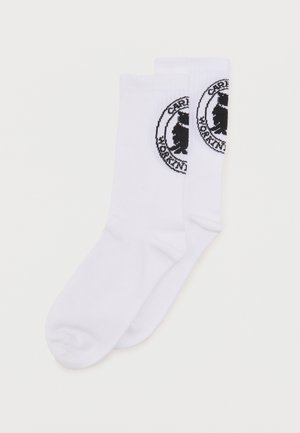 Paar weiße Mid-Calf-Socken mit schwarzem runden Logo, das einen Bären und den Schriftzug "CARL MORRISON" nahe dem oberen Bündchen zeigt.