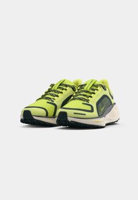 Limegrønne sneakers med et mesh-overdel, sorte accenter og struktureret gummisål. Har tykke snørebånd og et synligt brandlogo.