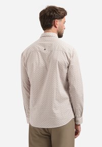 Licht beige overhemd met lange mouwen, voorzien van een subtiel geometrisch patroon, een button-down kraag en een enkele rugplooi. Afgewerkt met geknoopte manchetten.