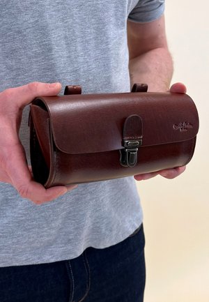 Braune Lederhandtasche mit einer Klappe, metallischem Verschluss und zwei Schlaufen oben. Glatte Textur und leicht abgerundete Ecken. Kompaktes und funktionales Design.
