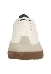 Vita läder och beige mockaskor med svarta accenter, platta snören och en texturerad gummisula. Rund tå och slät yta.