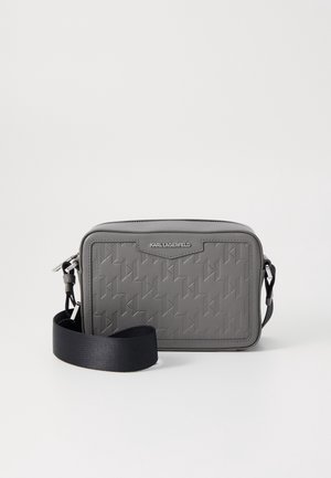 Sac bandoulière gris Karl Lagerfeld avec motif embossé et bandoulière noire réglable sur fond blanc.