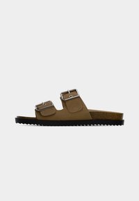 Καφέ σαμπό με δύο ρυθμιζόμενες ασημένιες αγκράφες και παχύ πάτο από φελλό με μαύρη ανάγλυφη σόλα.