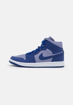 Zapatilla alta en azul marino y lavanda con logo de Nike, cordones, puntera perforada y suela blanca sobre fondo liso.