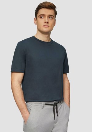 Donkerblauwe crewneck t-shirt, korte mouwen, gladde textuur, gecombineerd met lichtgrijze broek met een touwsluiting in de taille.