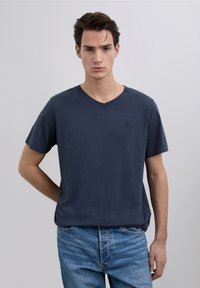 Camiseta azul marino de manga corta con cuello en V, hecha de algodón suave, con un diseño sencillo, detalles mínimos y un ajuste relajado.