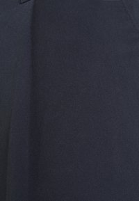 Marinfärgad tyg med en fin, strukturerad yta och en lätt lyster. En vertikal söm ger dimension till den klassiska designen.