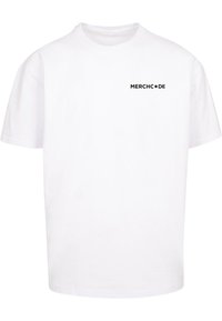 Hvid bomulds T-shirt med rund halsudskæring og korte ærmer. Sort tekst, der er trykt foran med teksten "MERCHC•DE" på venstre brystområde.
