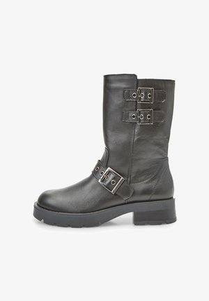 Stivale nero in pelle fino al ginocchio con due fibbie metalliche e una suola spessa e texture. Presenta una finitura liscia e un design robusto.