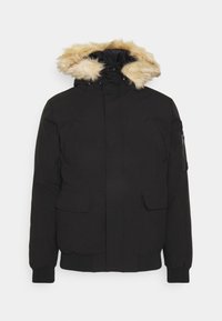 Veste noire matelassée avec capuche bordée de fourrure. Comprend des poches zippées et à rabat, des poignets élastiqués et un tissu solide texturé.