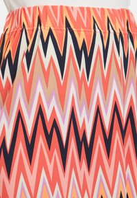 Gonna a fantasia con motivi a zigzag in tonalità di rosso, rosa, beige e nero. Realizzata in tessuto morbido con una cintura elastica.