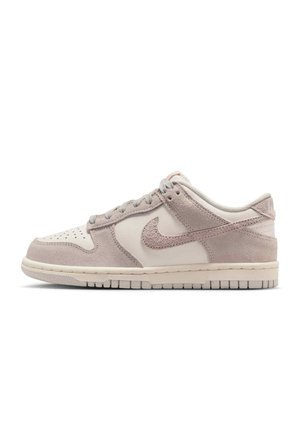 Low-top sneaker in beige en lichtbruin suède met geperforeerde neus, vetersluiting en Nike-swoosh aan de zijkant.