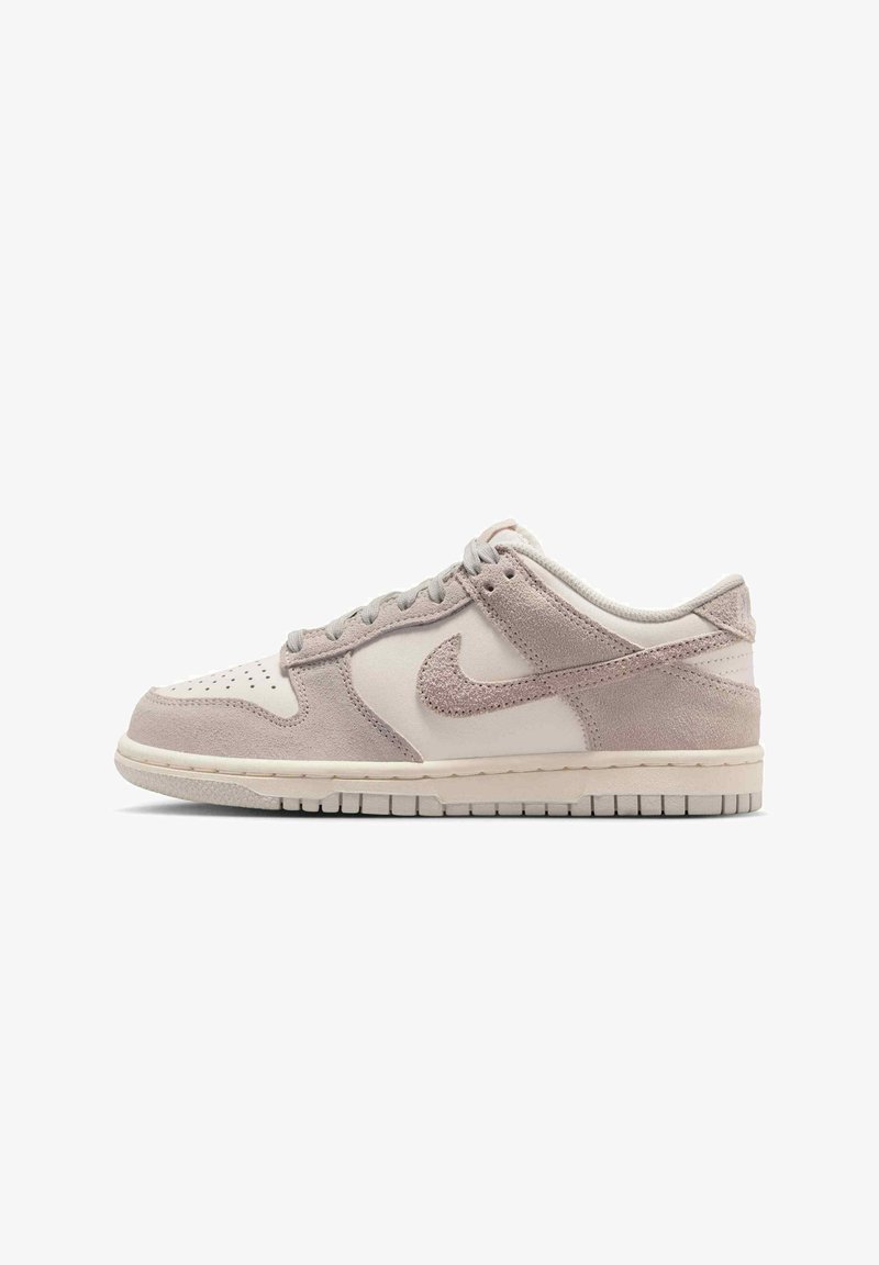 Lavtopsneaker i beige og lysebrun ruskind med perforeret tå, snørelukning og Nike-swoosh på siden.