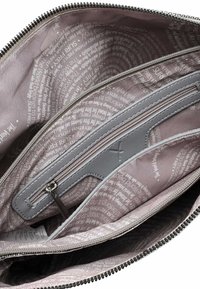 Interno di una borsa in tessuto grigio con più scomparti, dotato di una texture liscia, una sezione con zip e parole stampate su uno sfondo chiaro.
