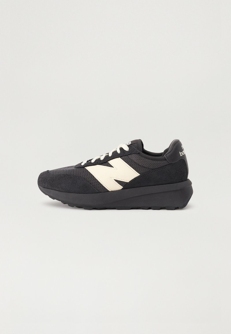 Fekete sneaker, bársony és hálós felsőrésszel, fehér logóval, texturált talppal és fűzőzárral. Lekerekített orrész és párnázott kialakítás.