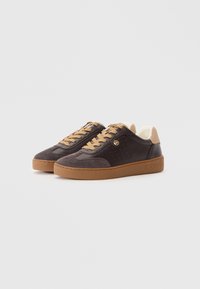 Pair of dark brown and tan leather sneakers with gum soles, beige laces, and perforated sides, positioned on a white surface.