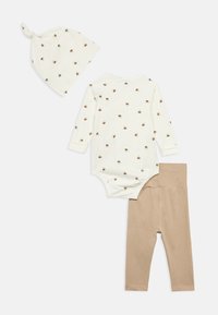 Το σετ περιλαμβάνει ένα μπεζ πλεκτό καπέλο με κόμπο και ένα κρεμ φορμάκι με καφέ σχέδια μελισσών, συνδυασμένο με ανοιχτό καφέ κολάν.