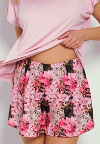 Kwiatowe szorty do spania na czarnym tle, z wzorem różowych i białych kwiatów, elastyczną talią i luźnym krojem. Do kompletu różowy top.