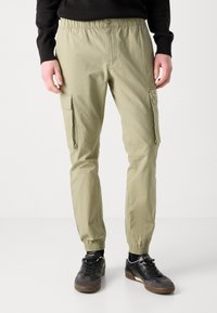 Lichtkhaki cargobroek met zijzakken, elastische tailleband en boorden. Gemaakt van een lichtgewicht stof, met een gladde textuur en een minimalistisch ontwerp.
