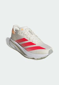 Lightweight athletic shoe in white mesh with pink gradient stripes, grey sole, and orange accents on the heel. Features pronounced lacing system.
